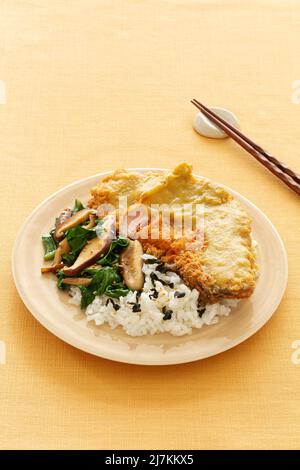 Von oben aus schmackhaftes Katsu-Muskat mit gebratenem Huhn und Sauce serviert mit Reis und Pilzen auf gelbem Hintergrund mit Essstäbchen Stockfoto