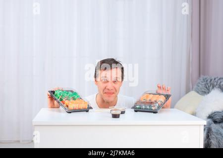 Der kaukasische Mann probiert zum ersten Mal asiatische Sushi-Brötchen Stockfoto