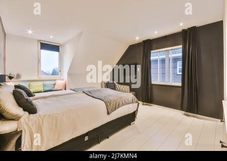 Breites, komfortables Bett mit warmen Decken und weichen Kissen im trendigen Schlafzimmer des modernen Apartments Stockfoto