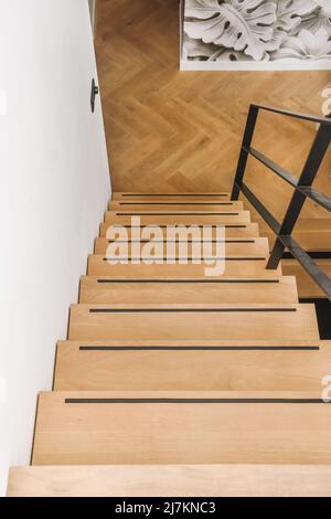 Von oben Holztreppe mit Metallgeländer in moderner Wohnung mit Holzboden tagsüber Stockfoto