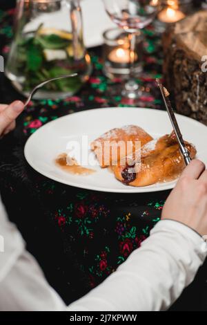 Frau, die fliegende Brötchen mit Früchten auf einem weißen Teller isst Stockfoto