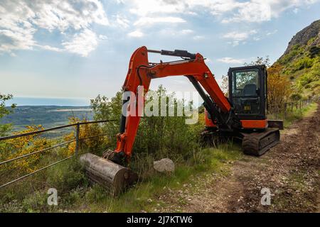 Bagger auf der Straße des Touristen in der Region Konavle in der Nähe von Dubrovnik. Die Straße am Hang des Berges über dem Tal. Stockfoto