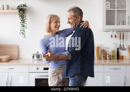 Liebevolles Seniorenpaar, das in der Küche Zeit zusammen genießt und tanzt Stockfoto