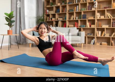 In voller Länge Porträt der asiatischen Dame Training auf Sportmatte, tun abs-Training, Training ihrer Kernmuskeln zu Hause Stockfoto