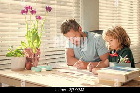 Bärtiger Vater schreibt Schulaufgaben mit seinem Sohn im Klassenzimmer, Wissen Stockfoto