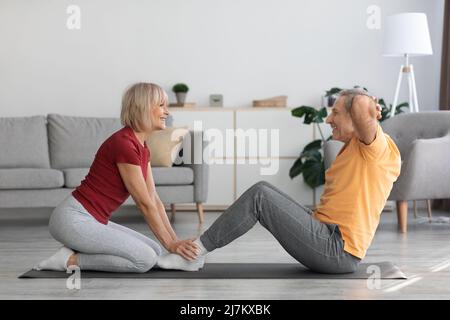 Sportliche ältere Dame trainiert mit ihrem Mann zu Hause Stockfoto