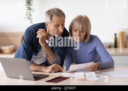 Ein älteres Paar, das mit einem Laptop am Tisch sitzt und Rechnungen bezahlt Stockfoto