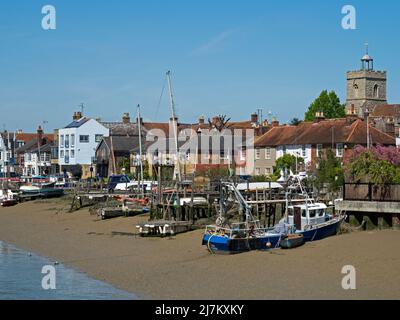 Boote, die am Strand vor der Mündung des Flusses Colne festgemacht wurden, mit den alten Gebäuden der Stadt Wivenhoe, Essex, England, Großbritannien Stockfoto