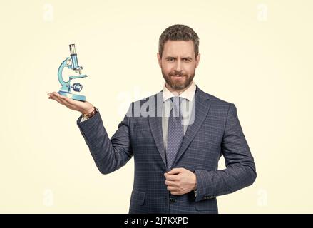 Schöner Geschäftsmann Mann in Anzug präsentiert moderne Mikroskop isoliert auf weiß, Research Investor. Stockfoto