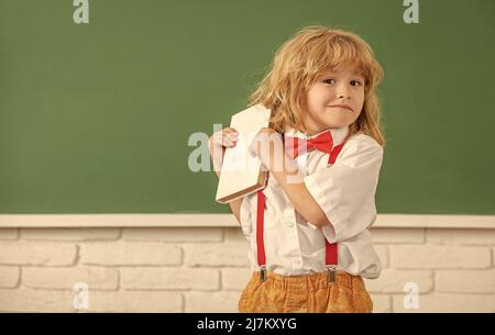 Kindheitsentwicklung. Kind mit Buch. Kopierraum. Fröhlicher Teenager-Junge im Klassenzimmer. Stockfoto