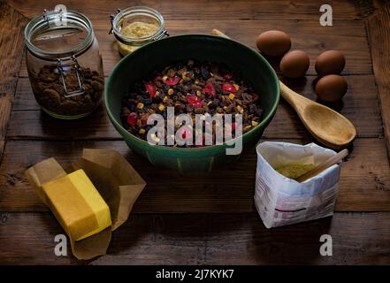 Zutaten, die fertig zusammengestellt sind, um einen Obstkuchen auf einem dunklen Holztisch zu machen. Stockfoto