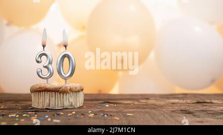 Happy Birthday Karte mit einer Kerze in einem Cupcake vor dem Hintergrund von Ballons. Kopieren Raum Happy Birthday mit Cupcake-Ziffer Stockfoto