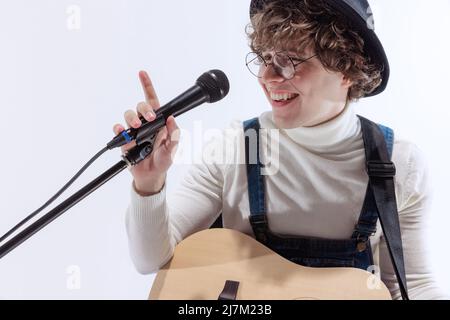 Porträt eines jungen Emotiona-Mannes, Musiker, der akustische Gitarre spielt und singt. Konzept von Kunst, Musik, Stil und Kreation Stockfoto