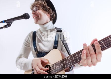 Porträt eines jungen Emotiona-Mannes, Musiker, der akustische Gitarre spielt und singt. Konzept von Kunst, Musik, Stil und Kreation Stockfoto