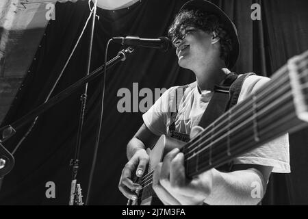 Wiederholung der Retro-Musikband im Musikstudio. Junger Musiker, der akustische Gitarre spielt und singt. Probenbasis. Konzept von Kunst, Musik, Stil und Stockfoto