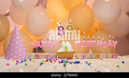 Schöner Hintergrund Happy Birthday Nummer mit brennenden Kerzen, Geburtstagskerzen in rosa Buchstaben. Festlicher Hintergrund mit Ballons Stockfoto
