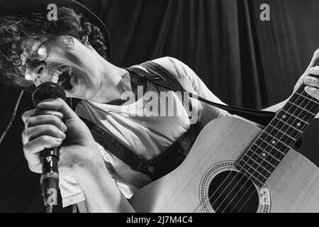 Wiederholung der Retro-Musikband im Musikstudio. Junger Musiker, der akustische Gitarre spielt und singt. Probenbasis. Konzept von Kunst, Musik, Stil und Stockfoto