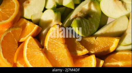 Das Konzept der gesunden Ernährung. In Scheiben geschnittene Orange saftige Orangen und grüne Äpfel liegen nebeneinander Draufsicht. Horizontales Banner mit Sommerfrüchten. Stockfoto