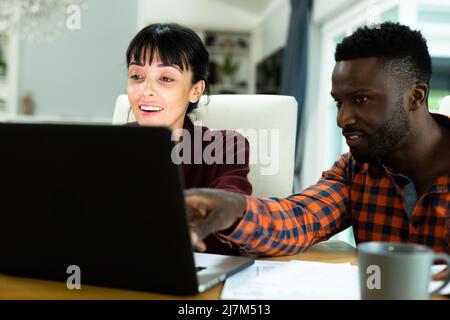 Multirassische junge Paar diskutieren Haushaltsausgaben Budget über Laptop zu Hause. Unverändert, Lebensstil, Zweisamkeit, Finanzen, Planung, Berechnung, Stockfoto