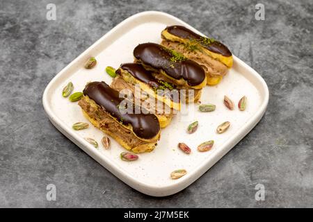 eclair-Schokoladenkuchen. Pistazie und eclair-Schokoladenkuchen auf dunklem Hintergrund. Nahaufnahme Stockfoto