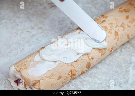 Der Konditor schmiert die Creme auf frisch gebackene Baiser-Brötchen Stockfoto