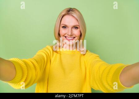 Foto von positiven gealterten Dame machen Selfie auf Herbst Urlaub tragen Strickmode Pullover isoliert grünen Hintergrund Stockfoto