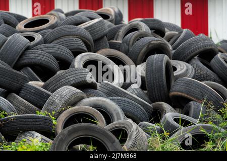 Haufen gebrauchter Reifen. Altreifen werden zum Recycling oder auf Deponien abgelagert. Schwarzer Gummireifen des Autos. Stapel von gebrauchten Reifen auf Recycling-Produktionshof. Stockfoto