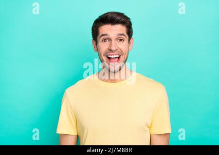 Foto von beeindruckt Brunet Millennial Kerl tragen gelbe T-Shirt isoliert auf türkisfarbenem Hintergrund Stockfoto