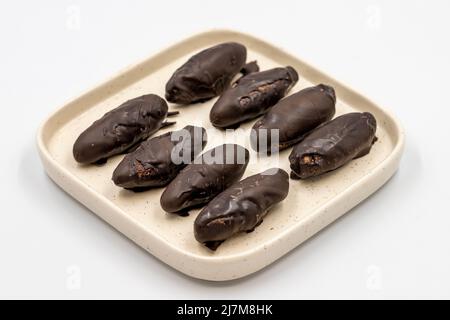 Spezielle Schokolade mit dunkler Außenseite und Kokosnuss innen. Dunkle Schokolade mit Kokosnussfüllung auf weißem Hintergrund. Nahaufnahme Stockfoto