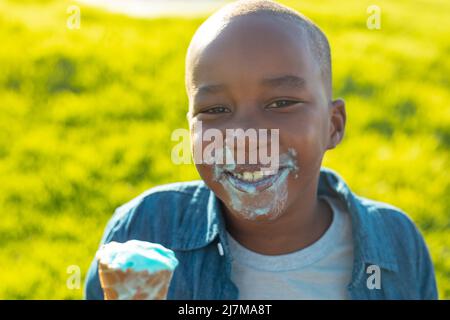 Porträt eines glücklichen afroamerikanischen Jungen mit einem chaotischen Gesicht, das im Sommer beim Essen von schmelzendem Eis zu sehen war Stockfoto