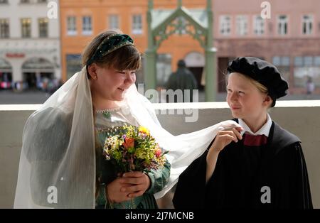 Lutherstadt Wittenberg, Deutschland. 10.. Mai 2022. Auf dem Balkon des Rathauses stehen Jasmin und Mika, Performer des Kinderlutherpaares für das Wittenberger Stadtfest „Lutherhochzeit“. Das Festival, das vom 10. Bis 12. Juni 2022 stattfindet, erinnert an die Hochzeit des ehemaligen Mönchs Martin Luther mit der Nonne Katharina von Bora im Jahr 1525. Jedes Jahr im Juni feiern die Wittenberger und ihre Gäste dieses Fest als ihr großes Fest. Kredit: Sebastian Willnow/dpa/Alamy Live Nachrichten Stockfoto