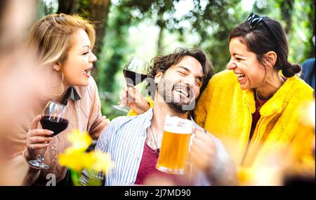 Junge Männer und Frauen haben Spaß Moment trinken Wein und Bier auf Gartenparty - Gesellschaftliches Treffen Lebensstil Konzept mit glücklichen Menschen genießen Treffpunkt Stockfoto