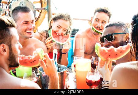 Fröhliche junge Freunde, die sich auf einer Bootsparty mit Wassermelone-Sangria und Champagner amüsieren - Freundschaftskonzept mit multikulturellen Menschen Stockfoto