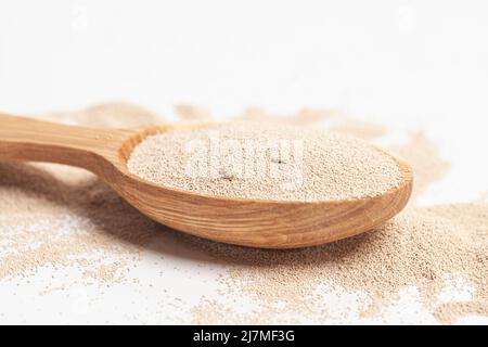 Aktive Trockenbackhefe-Granulat in Holzlöffel. Stockfoto
