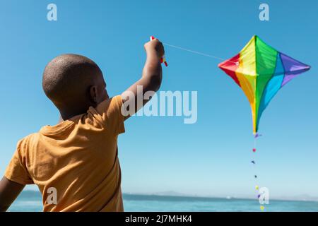 afroamerikanischer Junge genießt Drachen fliegen gegen blauen Himmel an sonnigen Tag Stockfoto