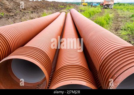 Neue Kanalrohre zur Verlegung in einem Graben- und Kanalbau auf die Baustelle gebracht, selektiver Fokus Stockfoto