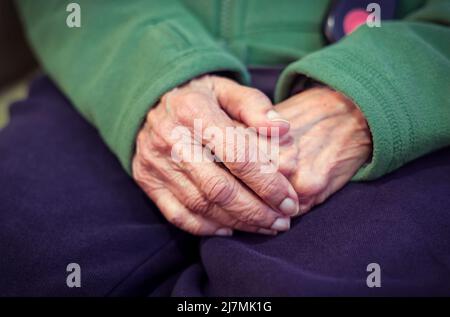 Nahaufnahme der Hände einer alten asiatischen Inderin mit faltiger Haut. Zeigt Konzepte zu Einsamkeit, Sorge, Demenz und psychischer Gesundheit. Stockfoto