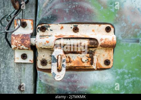 Nahaufnahme des rostigen Türschlosses an der Aluminiumtür Stockfoto
