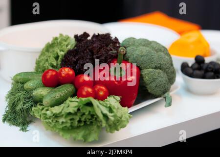 Zusammensetzung von Gemüse. Auf dem Teller sind Brokkoli, Kirschtomaten, Paprika, Gurken Stockfoto