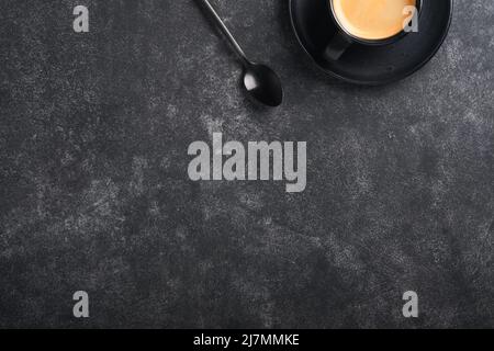 Hintergrund für Kaffee. Messlöffel mit gemahlenem Kaffee, Bohnen, Tasse und süßen Schokoladentrüffeln auf altem schwarzen Betontisch. Hintergrund der Speisen. Draufsicht Stockfoto