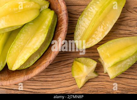 Starfruits mit Scheiben in einer Schüssel über einem Holztisch. Stockfoto