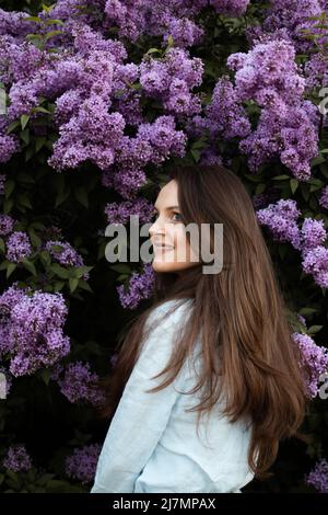 Junge schöne Brünette Frau riecht Fliederblüte im Frühling Stockfoto