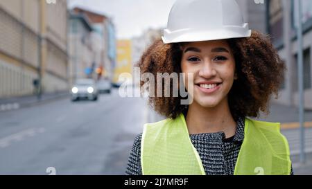 Weibliche Porträt Arbeiter Beruf close-up afroamerikanische Frau Mädchen mit lockigen Haaren Bauingenieur Profi trägt Schutzhelm im Stehen Stockfoto