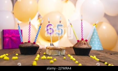 Schöne Geburtstagskarte für ein Mädchen mit einem Cupcake auf dem Hintergrund von Ballons. Alles gute zum Geburtstag Mädchen, Geschenkbox auf dem Hintergrund brennender Kerzen. Stockfoto