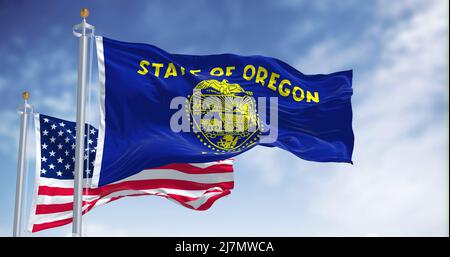 Die Staatsflagge von Oregon winkt zusammen mit der Nationalflagge der Vereinigten Staaten von Amerika. Im Hintergrund ist der Himmel klar. Oregon ist eine US-amerikanische St. Stockfoto