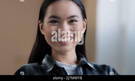 Nahaufnahme des weiblichen Gesichts mit perfekter Haut und natürlichem Make-up, das mit einem freundlichen, aufrichtigen Lächeln auf die Kamera blickt. Portrait asiatische Frau 20s Mädchen koreanische Dame Stockfoto