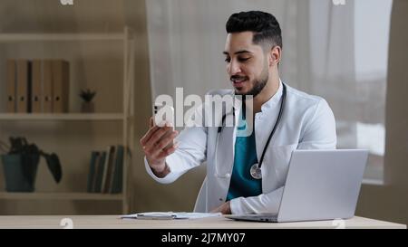 Männlicher Arzt Allgemeinarzt hispanic Mann, der Kunden online über mobile Telemedizin-Anwendung im Krankenhausschrank Remote berät Stockfoto