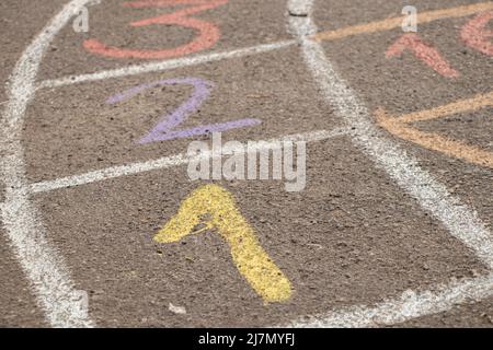 Auf dem Asphalt wird im Hof neben einem Haus in der Ukraine ein Kinderspiel mit Zahlen gezeichnet, auf der Straße ein Kinderspiel Stockfoto