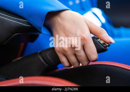 Eine weibliche Hand drückt einen Knopf und senkt die Handbremse. Stockfoto