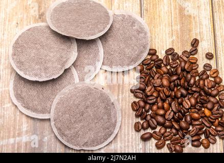 Draufsicht auf Kaffeepads und Kaffeebohnen auf einer rustikalen Holzoberfläche als Beispiel für verschiedene Kaffeerohprodukte. Flache Lay-Komposition Stockfoto